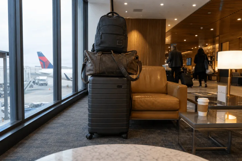 Front-camera view from an iPad in an airport lounge, showing several pieces of luggage by the window.